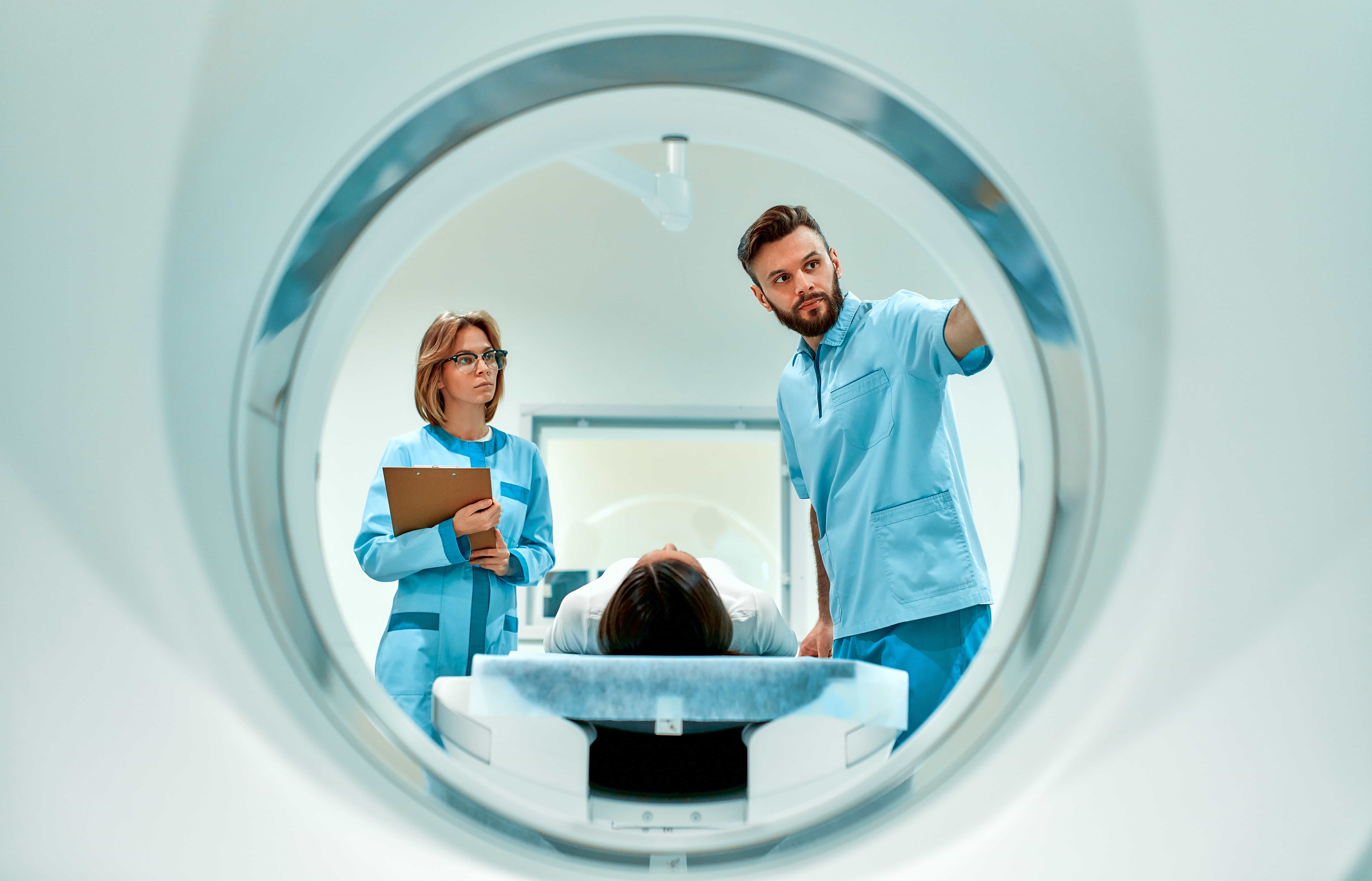 AdobeStock_425084473 The patient lies on CT or MRI, the bed is moved inside the machine, scanning her body and brain under the supervision of a doctor and a radiologist. In a medical laboratory with high-tech equipment.